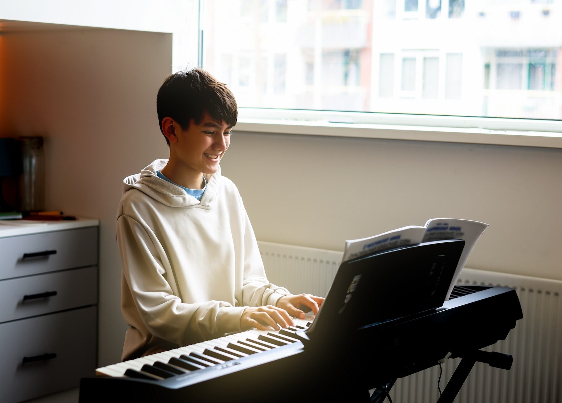 Middle school boy enjoy playing practicing electronic piano keyboard in his free time in his room at home